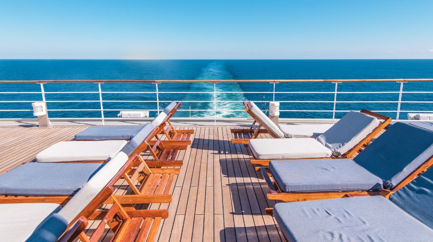 Chairs on the deck of a cruise ship, with water in the background.