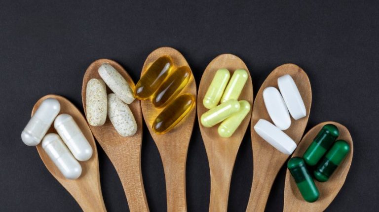 Six wooden spoons with different vitamins on them.