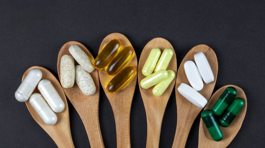 Six wooden spoons with different vitamins on them.