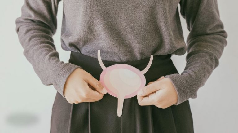 A woman holding a paper image of a bladder in front of her groin.