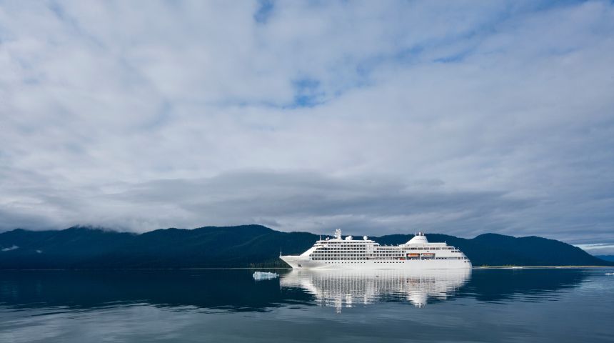 A cruise ship on the water, with small mountains in the background.