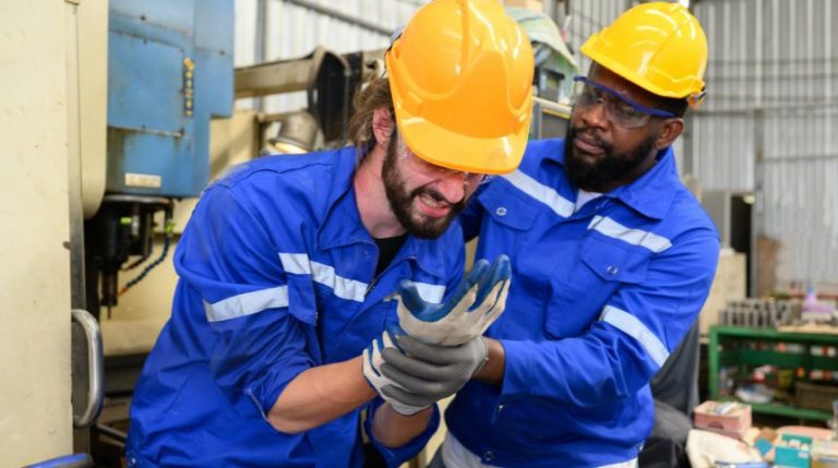A factory working holding his arm after getting hurt at work.