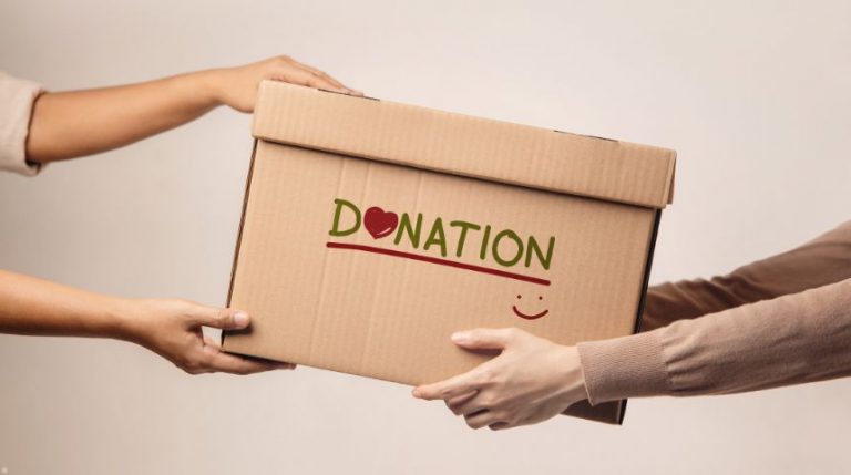 Two people holding a box that says "donations" on it